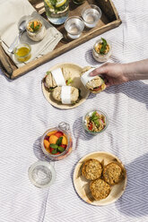 Hand taking sandwich from picnic blanket with vegetarian snacks - EVGF03108