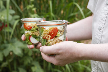 Person mit Gläsern mit vegetarischem Hafersalat - EVGF03111