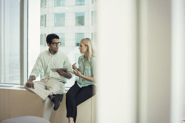 Business people with digital tablet sitting on window sill, discussing - WESTF21755