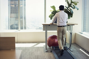 Businessman training on tread mill while using laptop - WESTF21756