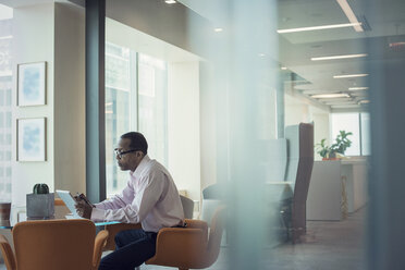 Businessman working alone in office using digital tablet - WESTF21812