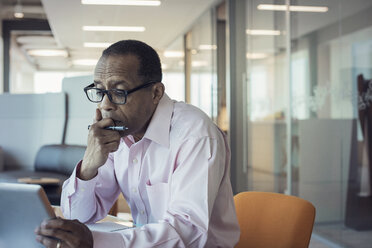 Businessman working alone in office using digital tablet - WESTF21813