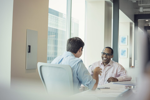 Zwei Geschäftsleute sprechen im Büro miteinander, lizenzfreies Stockfoto