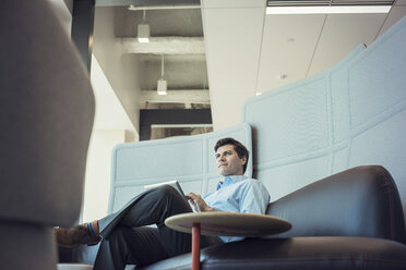 Businessman sitting in office, using digital tablet - WESTF21831