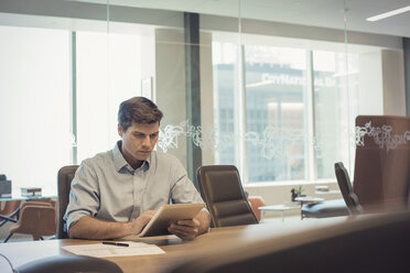Businessman sitting in office, using digital tablet - WESTF21833