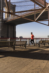 USA, New York City, Mann läuft am East River unter der Brooklyn Brige - UUF08819