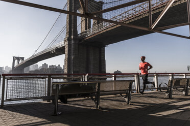 USA, New York City, Mann läuft am East River unter der Brooklyn Brige - UUF08821