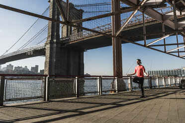 USA, New York City, Mann springt Seil am East River unter der Brooklyn Bridge - UUF08825