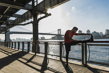 USA, New York City, sportive man stretching at East River - UUF08829