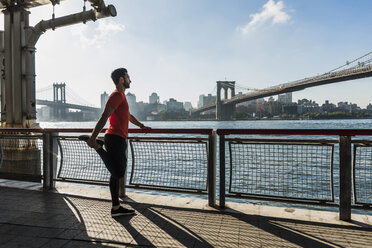USA, New York City, sportlicher Mann beim Stretching am East River - UUF08831