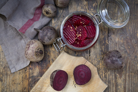 Einmachglas für eingelegte Rote Bete und ganze und geschnittene Rote Bete auf Holz, lizenzfreies Stockfoto