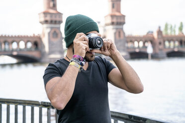 Germany, Berlin, man taking pictures with camera in front of Oberbaum Bridge - TAMF00705