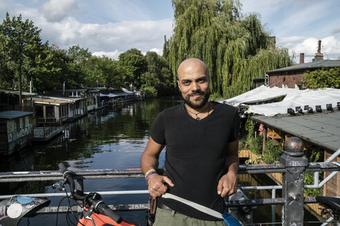 Deutschland, Berlin, Porträt eines Mannes mit Fahrrad auf einer Brücke - TAMF00711