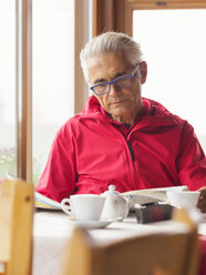 Älterer Mann sitzt in einem Café und liest Zeitung - LAF01770