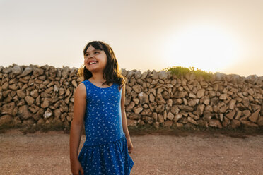 Portrait of happy little girl wearing blue dress at sunset - MGOF02565