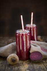 Gläser mit Rote-Bete-Smoothies mit Hanfsamen und ganzer und geschnittener Roter Bete auf Holz - LVF05512