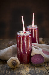 Glasses of beetroot smoothies with hemp seed and whole and sliced beetroot on wood - LVF05512
