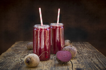 Two glasses of beetroot smoothies with hemp seed and whole and sliced beetroots on wood - LVF05513