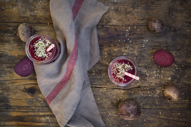 Two glasses of beetroot smoothies with hemp seed and whole and sliced beetroots on dark wood - LVF05515