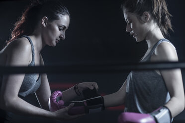 Woman helping female boxer putting on boxing gloves - ZEF11076