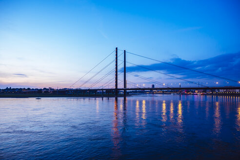 Deutschland, Düsseldorf, Blick auf die Rheinknie-Brücke mit dem Rhein im Vordergrund zur blauen Stunde - KRPF01908