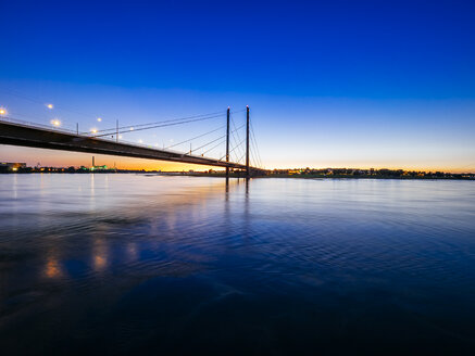 Deutschland, Düsseldorf, Blick auf die Rheinknie-Brücke mit dem Rhein im Vordergrund zur goldenen Stunde - KRPF01911