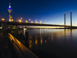 Deutschland, Düsseldorf, Blick auf beleuchtete Rheinknie-Brücke und Fernsehturm bei Nacht - KRPF01914