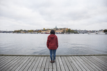 Schweden, Stockholm, Rückenansicht einer Frau, die auf einem Pier steht und auf die Stadt blickt - ABZF01438