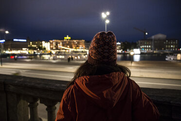 Rückenansicht einer Frau mit Blick auf die Stadt bei Nacht - ABZF01447