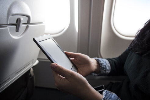 Frau sitzt im Flugzeug und benutzt ein E-Book, Teilansicht - ABZF01453