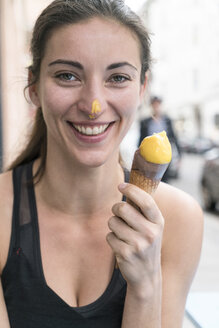 Portrait of smiling young woman with ice cream cone and ice cream at her nose - TAMF00728