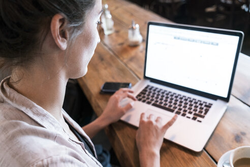 Junge Frau arbeitet mit Laptop in einem Café - TAMF00733