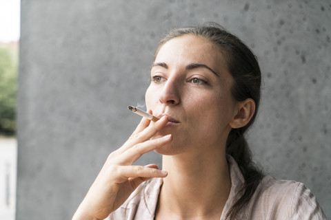 Porträt einer rauchenden jungen Frau, lizenzfreies Stockfoto