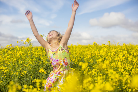 Kleines Mädchen tanzt im Rapsfeld, lizenzfreies Stockfoto