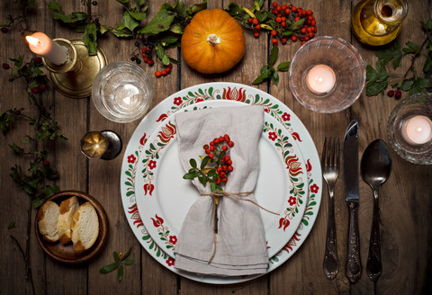 Autumnal laid table with pumpkin, holly and candle light stock photo