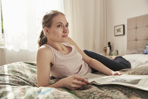 Frau liest Zeitung im Schlafzimmer - SUF00082