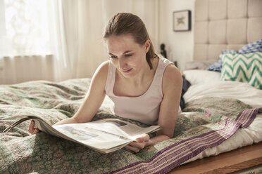 Frau liest Zeitung im Schlafzimmer - SUF00083