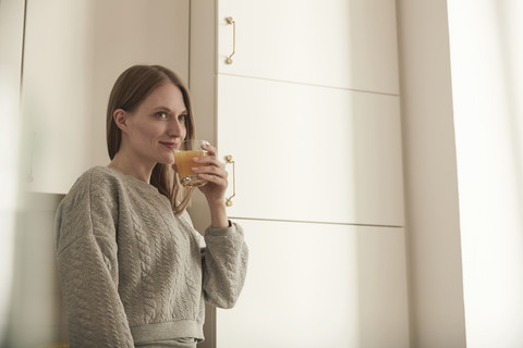 Frau trinkt Saft in der Küche, lizenzfreies Stockfoto