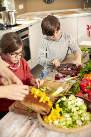 Junge und Mädchen hacken Gemüse in der Küche, lizenzfreies Stockfoto