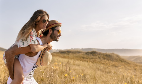 Mann nimmt seine Freundin in der Natur huckepack, lizenzfreies Stockfoto