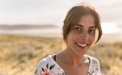 Portrait of smiling woman near the coast at evening sunlight - MGOF02586