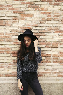 Modische junge Frau mit schwarzem Hut vor einer Fassade stehend - EBSF01865