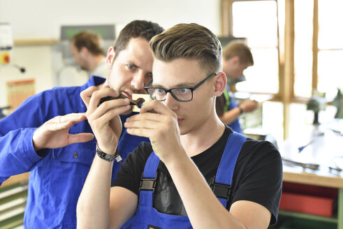 Instructor examining workpiece of trainee - LYF00591