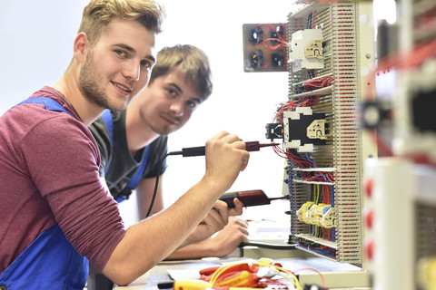 Zwei Elektrikerschüler bei der Arbeit an der Schalttafel, lizenzfreies Stockfoto