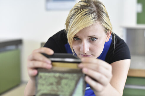 Female trainee examining workpiece in bench vice - LYF00624