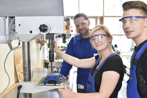 Portrait of smiling instructor with trainees at drill machine stock photo