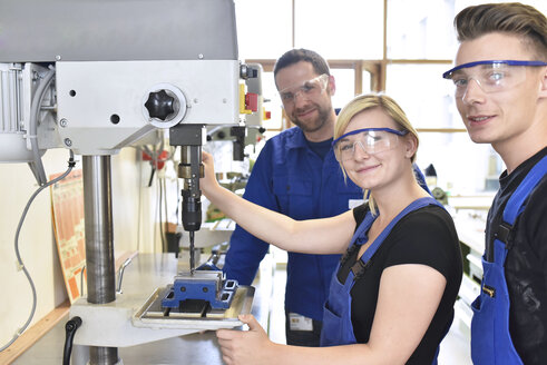 Portrait of smiling instructor with trainees at drill machine - LYF00627