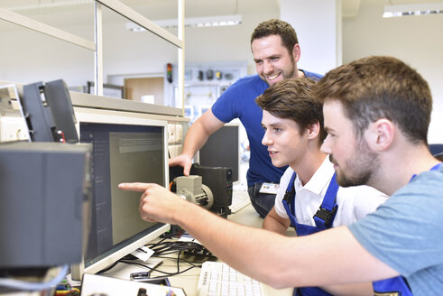 Technical instructor and students looking at computer screen - LYF00633