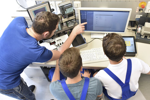 Technical instructor teaching students at computer screen - LYF00635