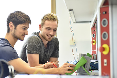 Smiling technical students looking at device stock photo